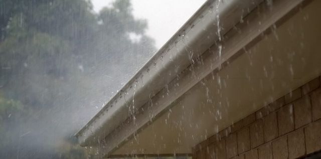 Rain running off a roof edge into a white gutter
